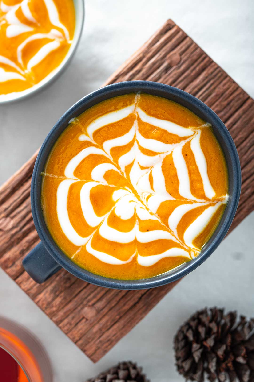 a cup of soup with a spiderweb made with cream