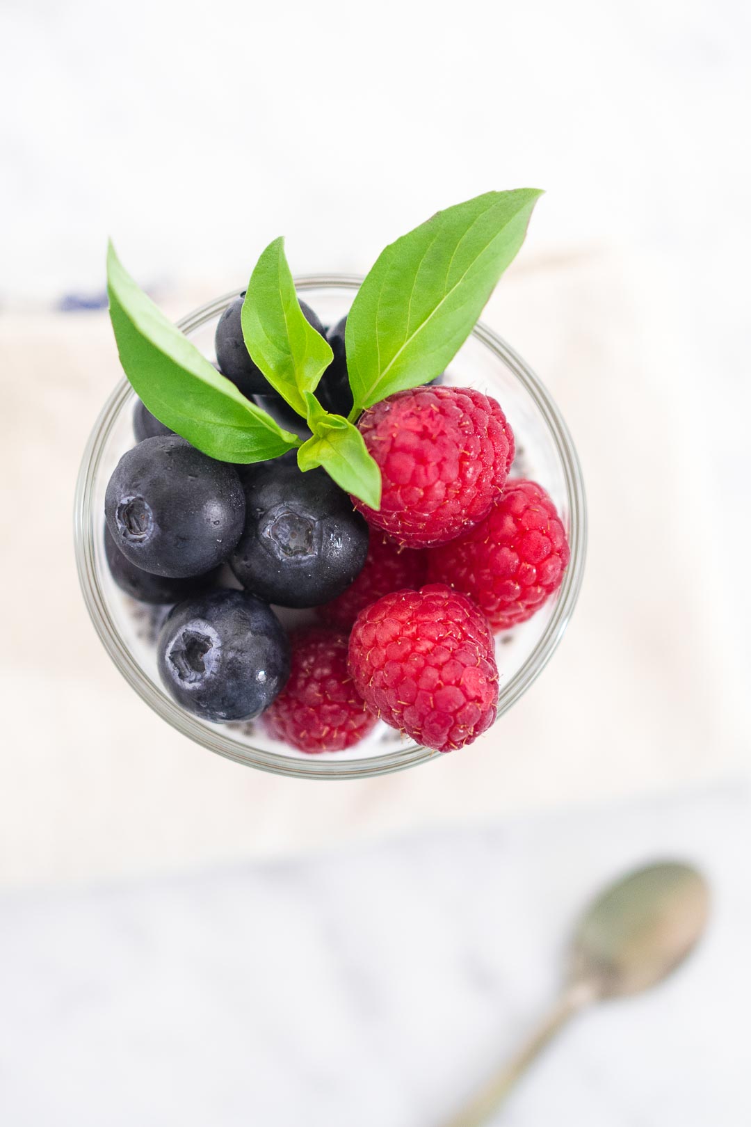 top view of a glass with blueberries and raspberries in it