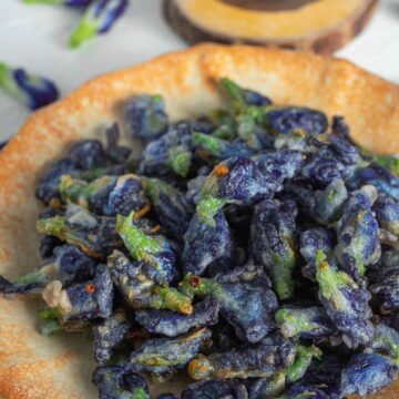 crispy deep fried butterfly pea flowers in a dish served with sweet chili sauce
