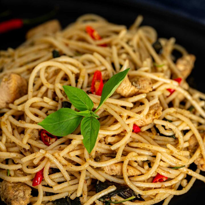 Thai green curry spaghetti with chicken on a black plate