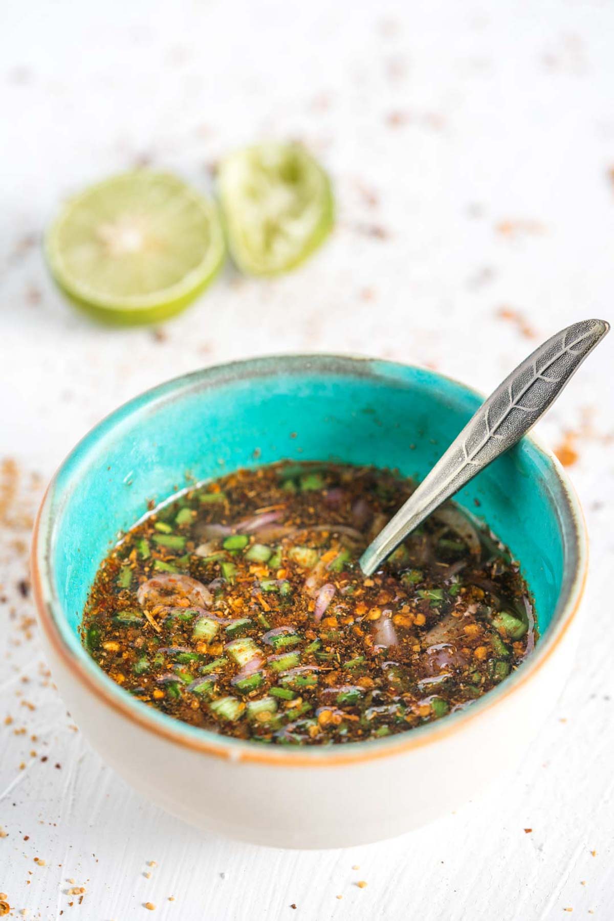 Thai chili dipping sauce in a bowl with fresh lime in the background