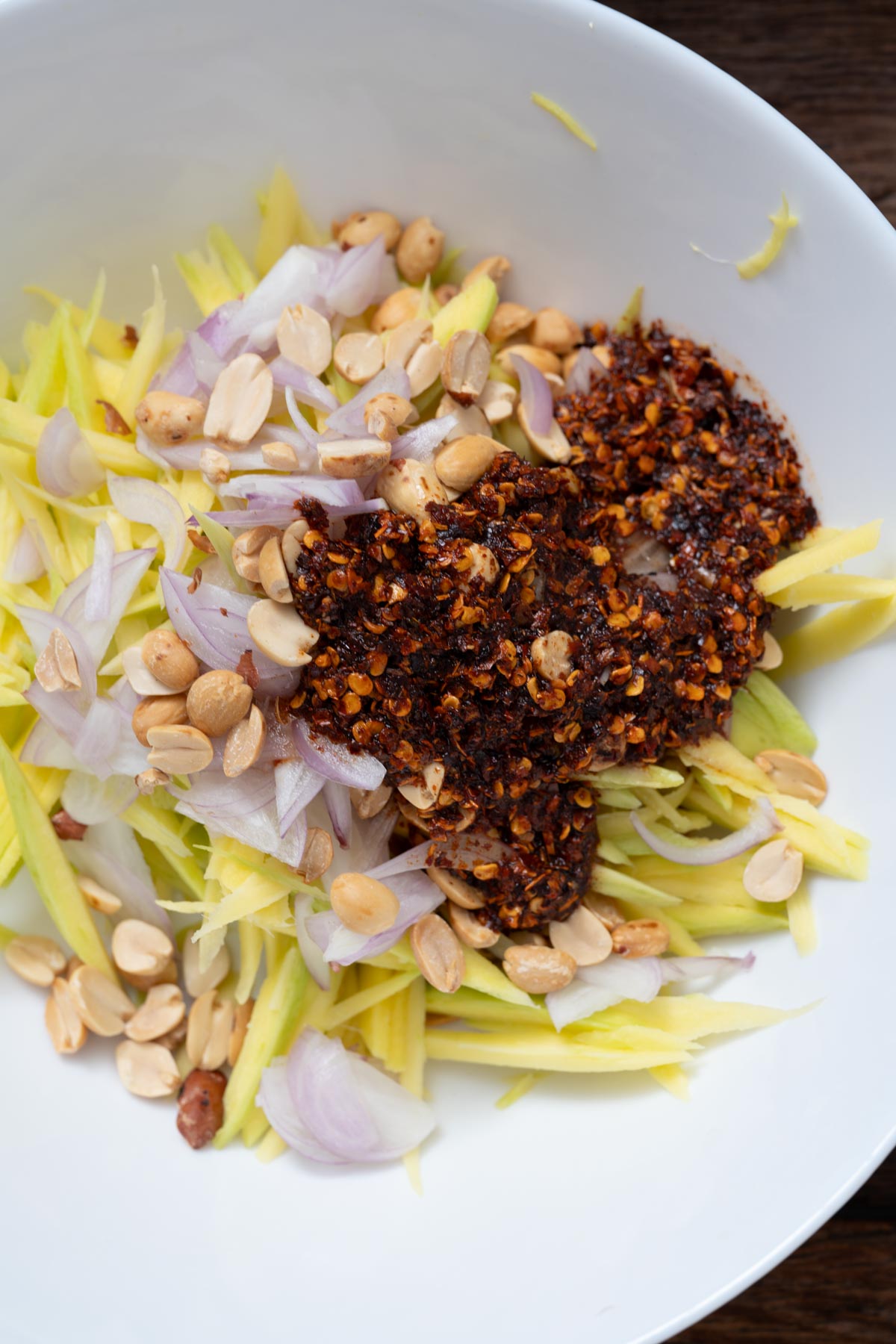 Thai green mango salad ingredients in a white bowl